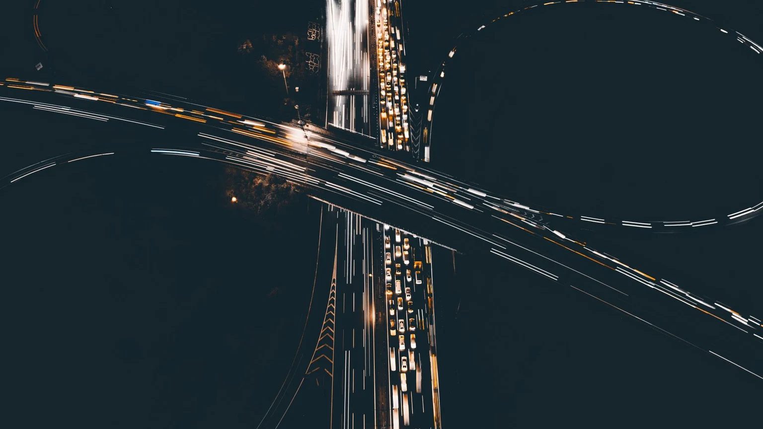 Overhead view of intersecting roads traced by vehicle lights at night